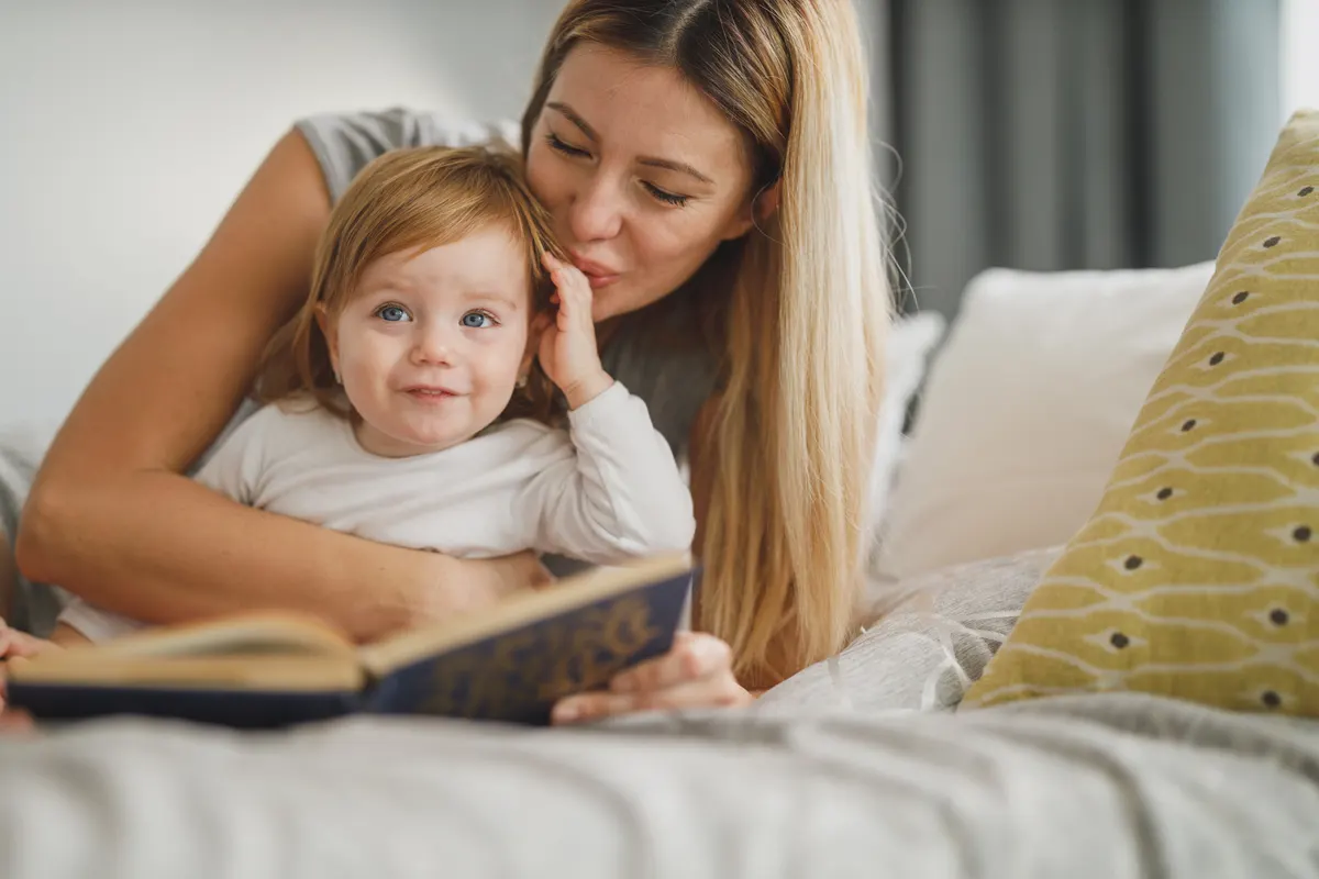 Mother kissing her young daughter at home