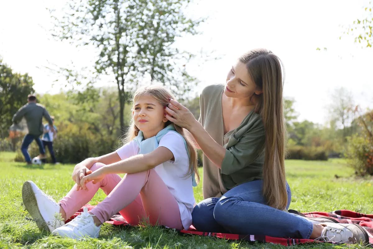 Mother braiding her daughter’s hair in a park
